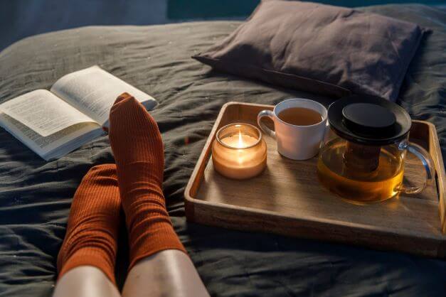 Turn Your Bedroom Into A Sleep Haven With These 10 Design Tips 3 women in bed with book and candle