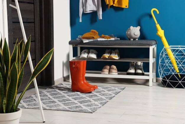 A bench with shoes and boots stored underneath