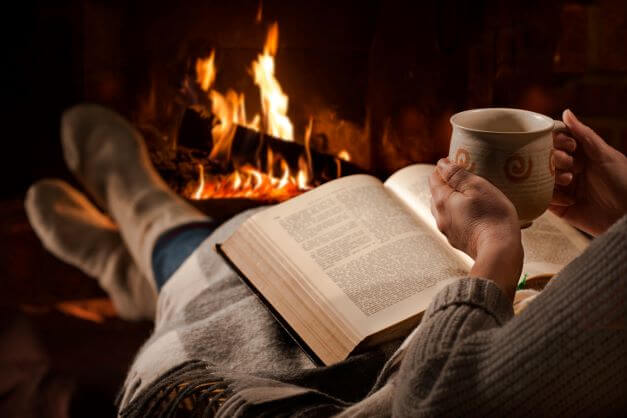 Stylish Fireplaces Guide, Advice and Considerations 3 A person sitting in front of a fireplace reading a book