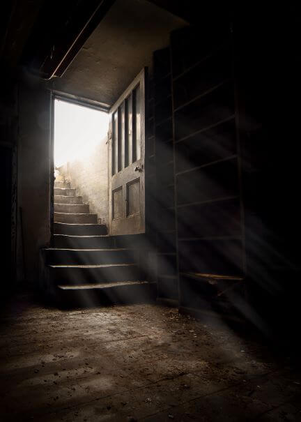 A dark cellar with a door open shedding light