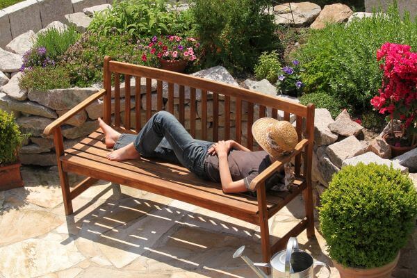 Lady relaxing by lying down on a wooden bench