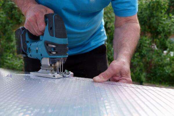 A person cutting a PVC sheet with electric jigsaw