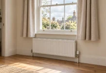 Short linen curtains ending above a white radiator, leaving the heater and valve uncovered.
